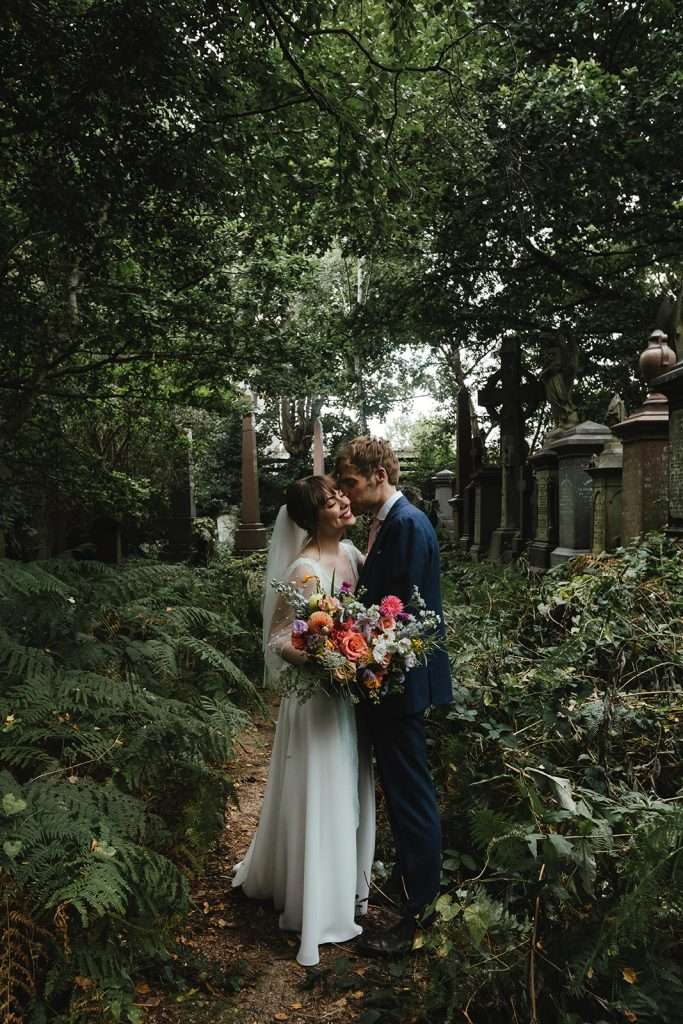 Candid couple laughing among trees at Abney Park Cemetery.