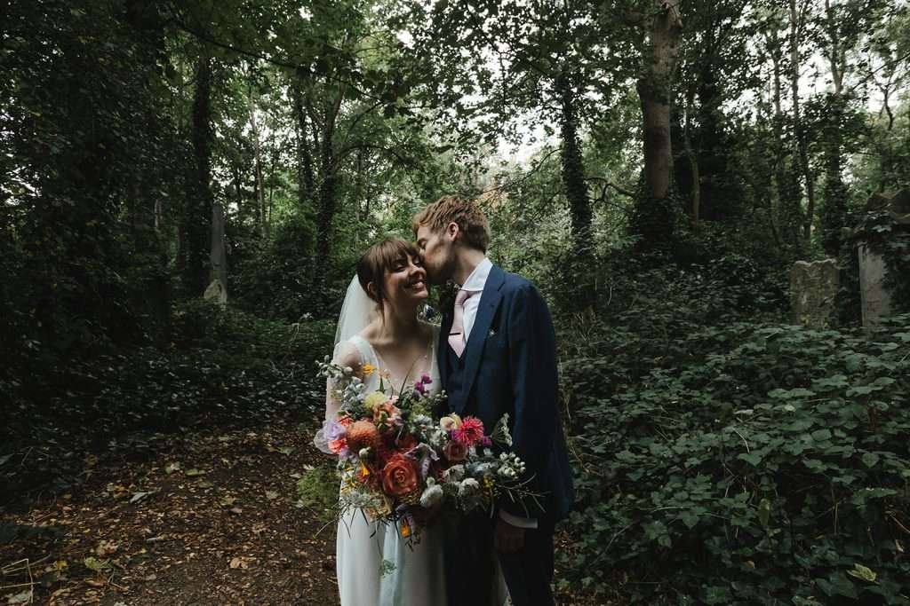 Bride and groom portraits at Abney Park Cemetery, London, surrounded by trees and historic tombs